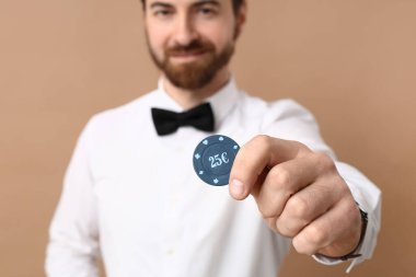 Bej arka planda poker çipi olan yakışıklı bir erkek bankacı, yakın plan.