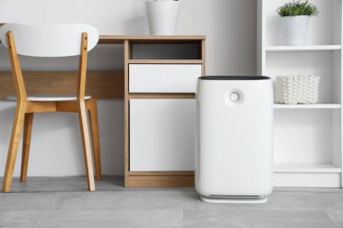 Oturma odasındaki masanın yanında hava temizleyici var.