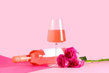 Bir bardak pembe şarap ve arka planda güzel güller.