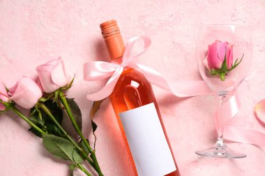 Cam kaplı bir şişe pembe şarap ve açık arkaplanda güzel güller