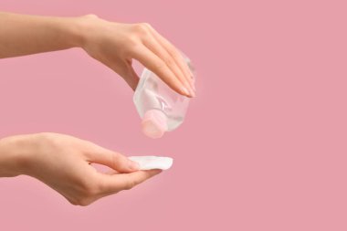 Pamuk kaplı kadın elleri ve pembe arka planda bir şişe mikiler suyu.