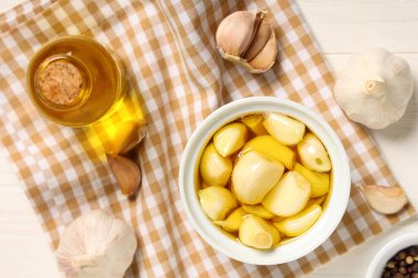 Beyaz ahşap arka planda bir şişe taze sarımsak yağı.