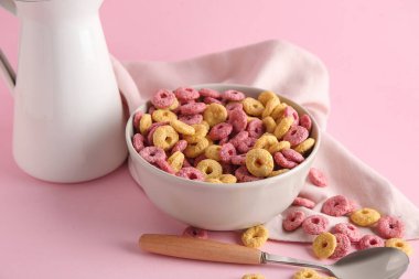 Pembe arka planda renk mısır gevreği halkaları olan kase, yakın plan.