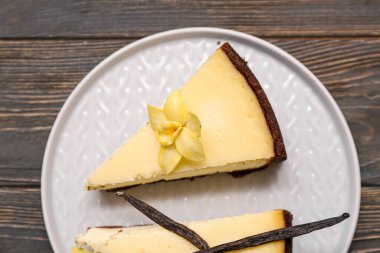 Siyah ahşap arka planda tatlı vanilyalı cheesecake tabağı, yakın plan.