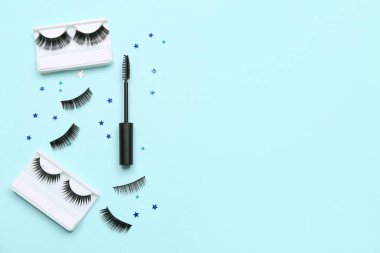 Maskara fırçası ve mavi arka planda pulları olan farklı takma kirpikler.