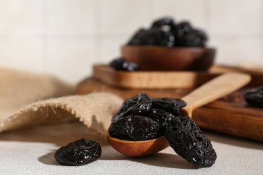 Tahta kaşık ve kase, beyaz masada kurutulmuş kuru erik.