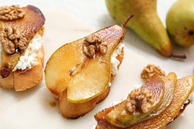 Beyaz arka planda ricotta peynirli ve cevizli armut bruschetta, yakın plan.