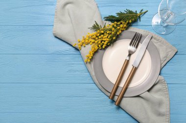Mavi ahşap arka planda mimoza çiçekleri olan güzel bir masa.