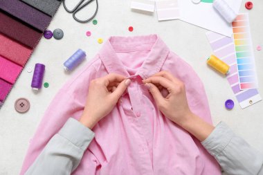 Beyaz masadaki pembe gömleğe kadın dikiş düğmesi, üst görünüm