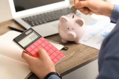 Ofisteki kumbaranın yanında hesap makinesiyle çalışan erkek eller. Yakın çekim.