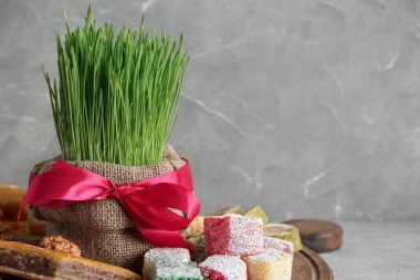 Gri grunge masasında yeşil buğday çimi, geleneksel baklava ve Türk lokumu olan pano, yakın plan. Nowruz Bayram kutlaması