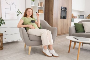 Evdeki koltukta kurutulmuş kuru erikli hamile bir kadın.