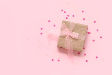 Pembe arka planda hediye kutusu ve konfeti.