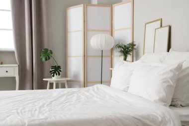 Beyaz battaniyeli rahat yatak ve şık yatak odasında yumuşak yastıklar, yakın çekim.