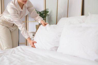 Yatak odasında yastığı kabartan genç kadın, yakın plan.