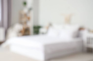 Beyaz battaniyeli rahat yatağın bulanık manzarası ve şık yatak odasında yumuşak yastıklar.