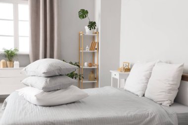 Gri battaniyeli rahat yatak ve şık yatak odasında bir yığın yumuşak yastık.