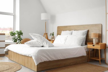 Beyaz battaniyeli rahat yatak ve şık yatak odasında yumuşak yastıklar.