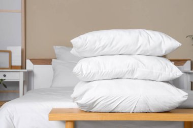 Beyaz battaniyeli rahat bir yatak ve şık bir yatak odasında, ahşap yatak başucunda bir yığın yumuşak yastık.