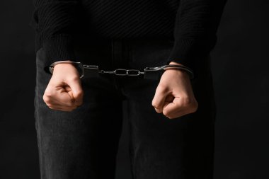 Siyah arka planda kelepçeli genç bir kadın, yakın plan.