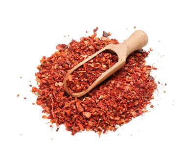 Beyaz arka planda bir yığın kırmızı biber ve ahşap kepçe.