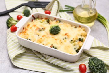 Gri arkaplanda lezzetli makarna, brokoli ve domatesli fırın yemeği.