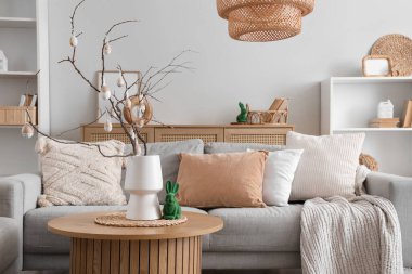 Şenlik salonundaki sehpanın üzerinde ağaç dalları ve Paskalya yumurtaları olan vazo, yakın plan.