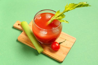 Yeşil arka planda kereviz ve domatesli bir bardak Bloody Mary.