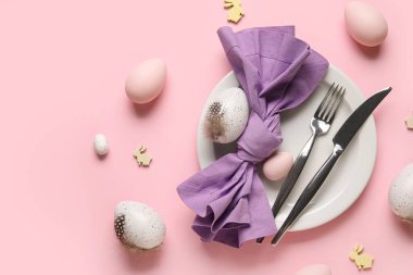 Paskalya yumurtaları ve pembe arka planda tahta tavşanlarla güzel bir masa.