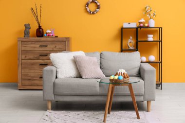 Oturma odasının içinde kanepe, paskalya pastası ve yumurtalar masada.