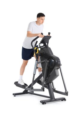 Modern egzersiz bisikleti üzerine beyaz arka planda antrenman yapan genç bir sporcu.