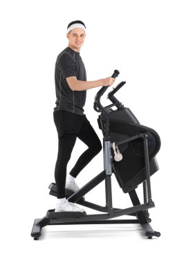 Modern egzersiz bisikleti üzerine beyaz arka planda antrenman yapan genç bir sporcu.