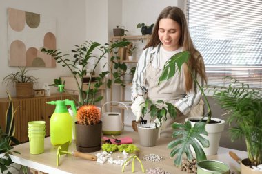 Bahçıvanlık malzemeleriyle evde çiçeklerle ilgilenen genç bir kadın.