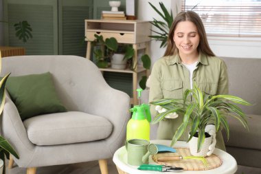 Evde çiçeklerle ilgilenen genç bir kadın.