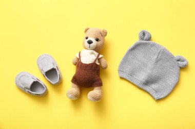 Örgü oyuncak ayı, bebek paçası ve sarı arka planda şapka.