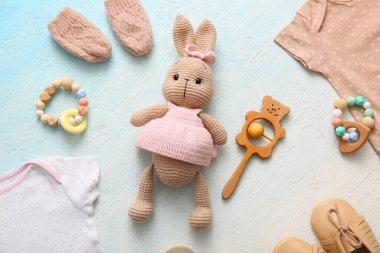 Hafif arka planda bebek aksesuarları, oyuncakları ve giysileri olan kompozisyon
