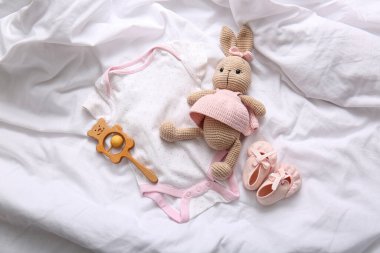 Bebek giysisi, patik ve oyuncaklar hafif yatakta