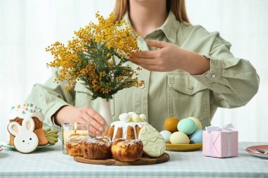 Paskalya kutlaması için masada mimoza çiçekli bir kadın var. Yakın çekim.