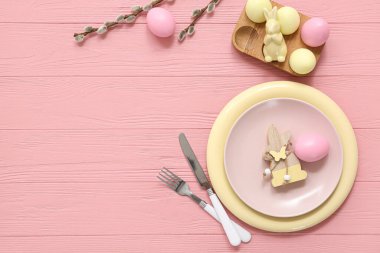 Beautiful table setting with Easter eggs, bunnies and pussy willow branches on pink wooden background