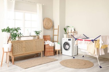 Modern çamaşır makinesi, kurutma askısı ve deterjan şişeleriyle şık bir çamaşır odası.