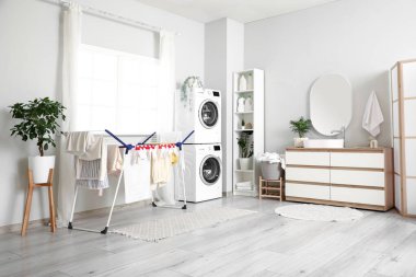 Modern çamaşır makineleri, kurutma rafları ve deterjan şişeleriyle şık bir çamaşır odası.