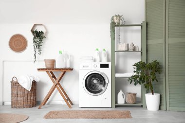 Modern çamaşır makinesi, raf ünitesi ve deterjan şişeleriyle şık bir çamaşır odası.