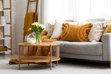 Oturma odasındaki masada vazo, lale ve Paskalya yumurtası.