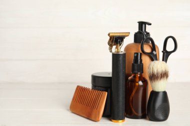 Makas, kozmetik ürünleri şişeleri ve beyaz ahşap arka planda fırçalarla modern budayıcı.