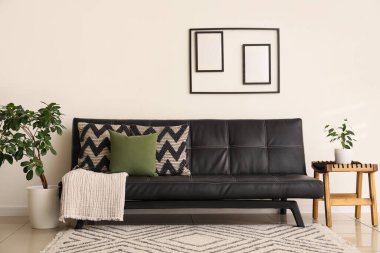 Şık oturma odasında yastıklı ve çiçekli modern siyah kanepe.