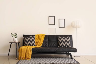 Modern siyah kanepesi, sehpası ve standart lambası olan şık bir oturma odası.