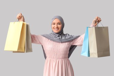 Gri arka planda alışveriş torbaları olan tesettürlü güzel Müslüman kadın