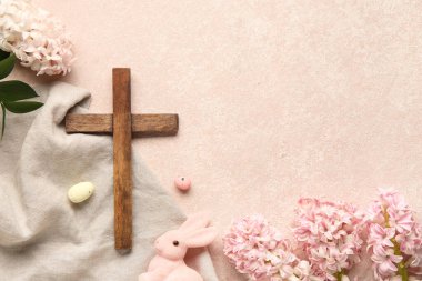 Ahşap haç, leylak çiçekleri, tavşan ve pembe grunge arka planda boyanmış yumurtalar. Paskalya kutlaması