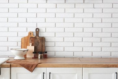 Mutfak aletleri beyaz tuğla duvarın yanında tezgahta.