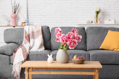 Salondaki masada pembe laleli ve paskalya yumurtalı vazo.